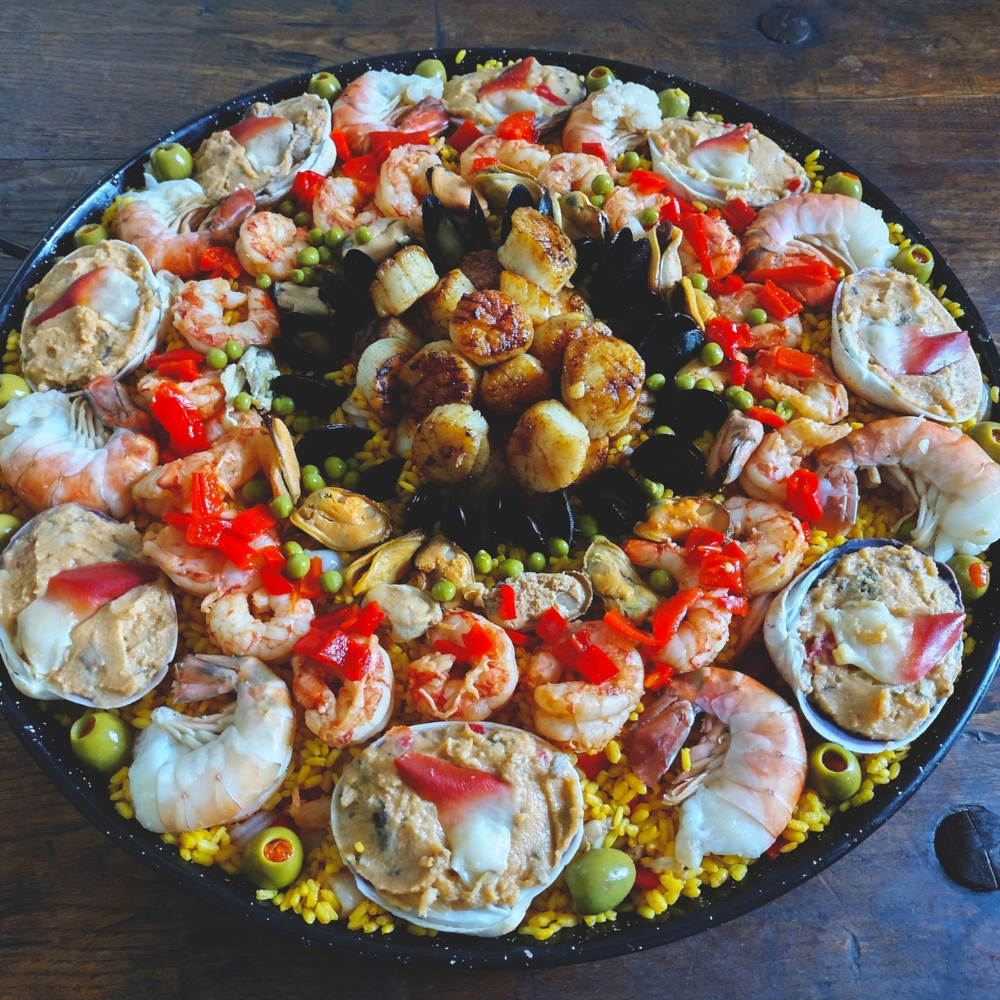Deluxe paella. Set of six for 75 guests. Paella 6. Hand-stuffed Cherrystone clams with sushi grade hokkigai surf clams, blue mussels, calamari, Key West pink shrimp, butter seared sea scallops.