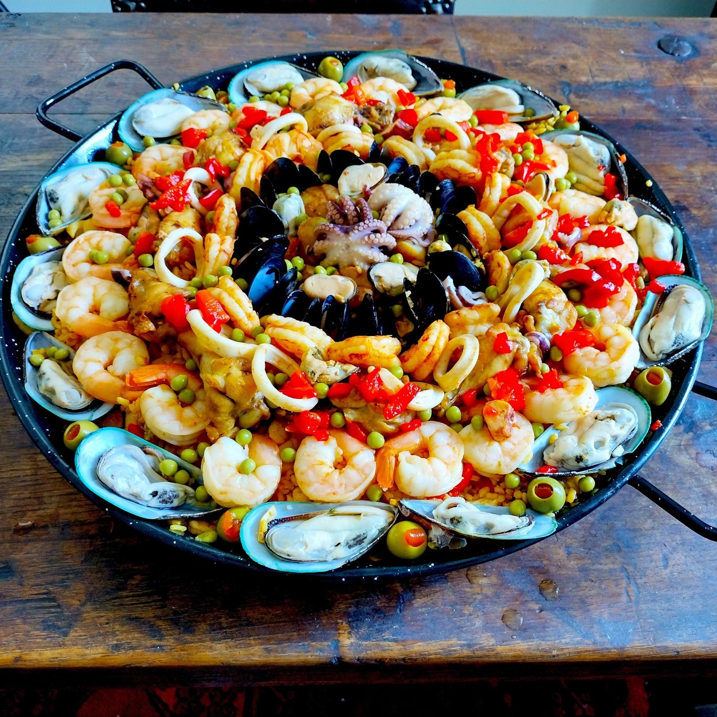 New Zealand green mussels, baby octopus, scallops, shrimp, calamari, chicken and chorizo paella for 12 guests.